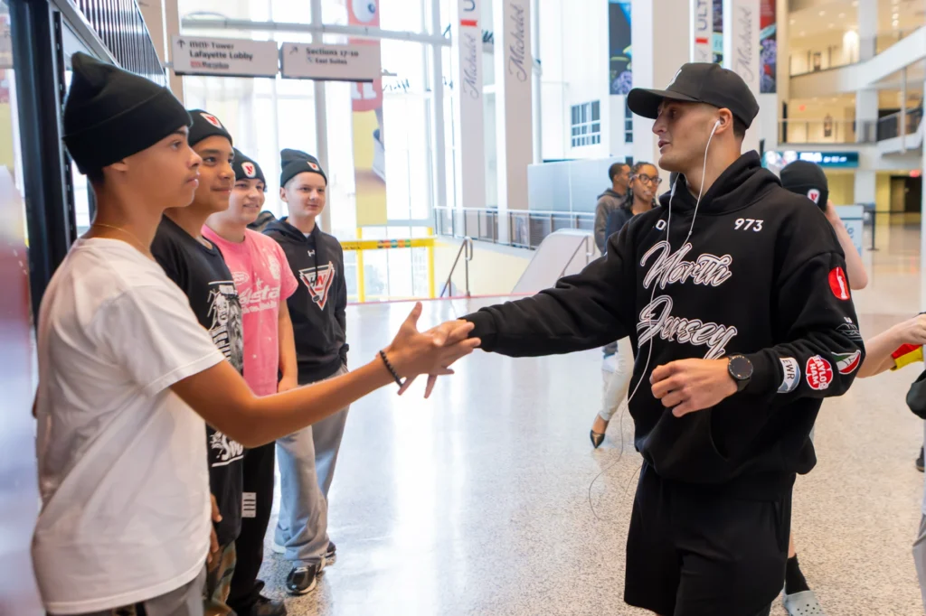 A fighter in a North Jersey hoodie shakes hands with Hockey in New Jersey players at the Matchroom Boxing press conference at Prudential Center
